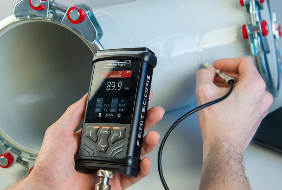Technician performing ferrite testing on a stainless steel weld using a Fischer Feritscope device.